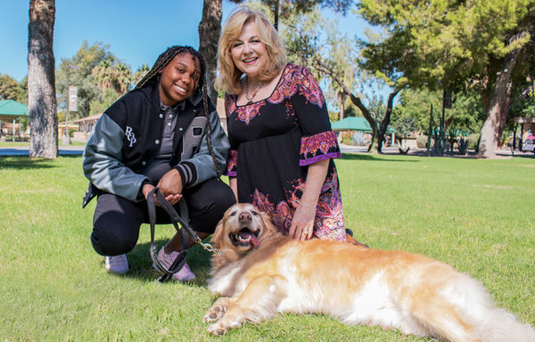 A woman with a Rite of Passage student holding a golden retriever