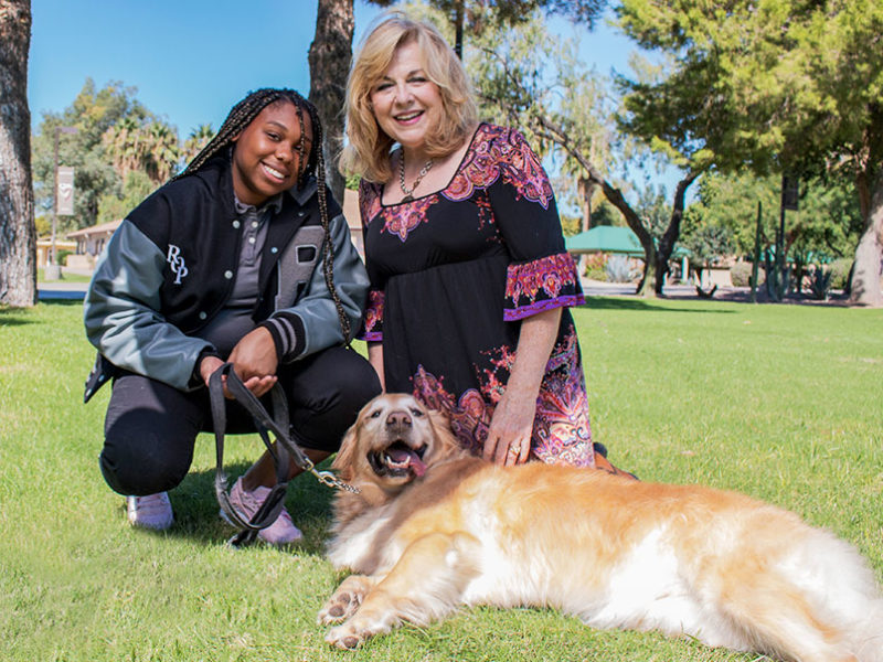 A woman with a Rite of Passage student holding a golden retriever