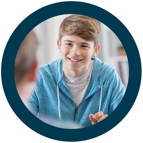 A young man smiling while listening to a teacher