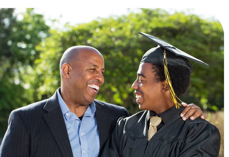 A man smiling at a younger man in a graduation gown