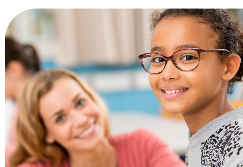 A young girl with glasses smiling with her teacher